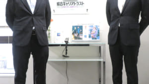 綜合キャリアトラスト池袋事業所の入口にて、社員Aさんと社員Bさんの写真